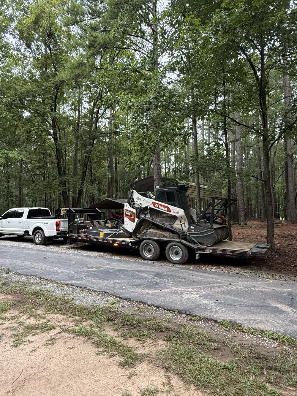 Brushkat truck and trailer hauling a Bobcat T86 with forestry mulcher